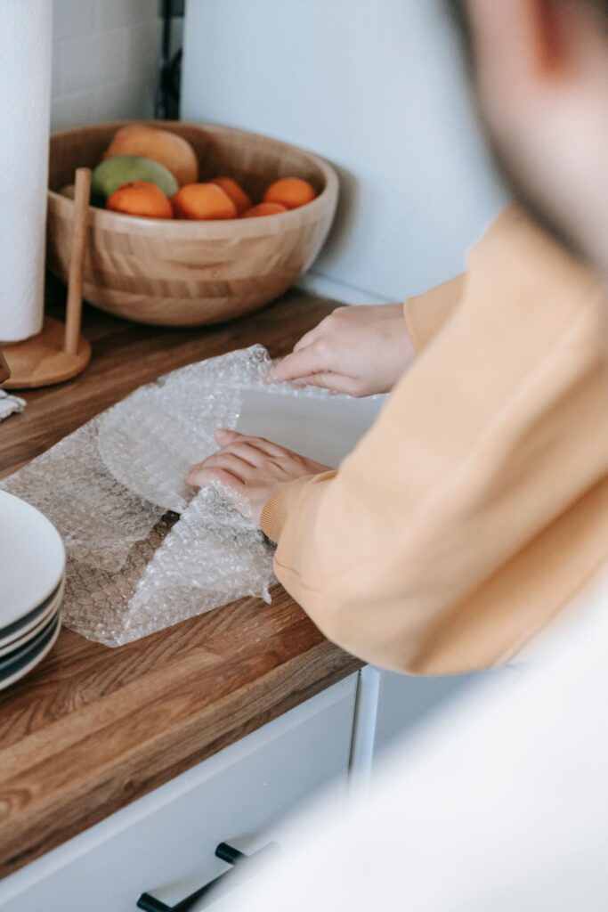 Hands carefully wrapping a plate in packing paper
